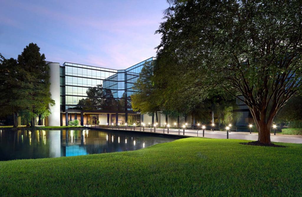 The exterior of Hyatt Regency Houston West, from across a green lawn.