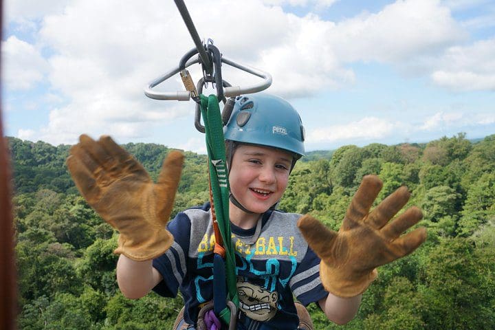 A young boy zip-lines along a course on the Manuel Antonio Canopy Tour - Longest Twin Zip Line in Central America tour.