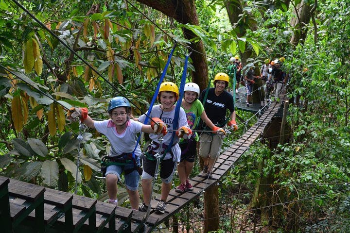 A family poses along a swing bridge on the Manuel Antonio Canopy Tour - Longest Twin Zip Line in Central America tour.