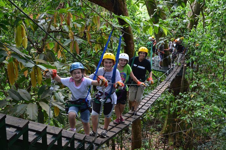 A family poses along a swing bridge on the Manuel Antonio Canopy Tour - Longest Twin Zip Line in Central America tour.