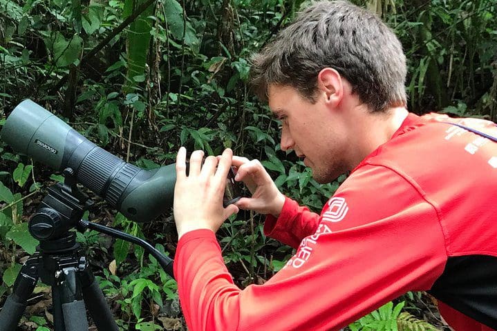 A man looks through a scope to see animals on the Manuel Antonio Park Private Nature Guided Tour Experience.