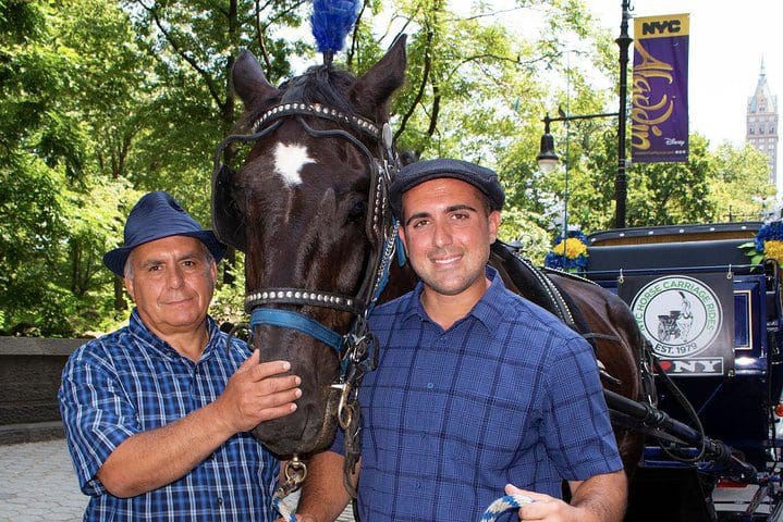 Two men stand near a horse waiting for guests to take the Official NYC Horse Carriage Rides in Central Park.