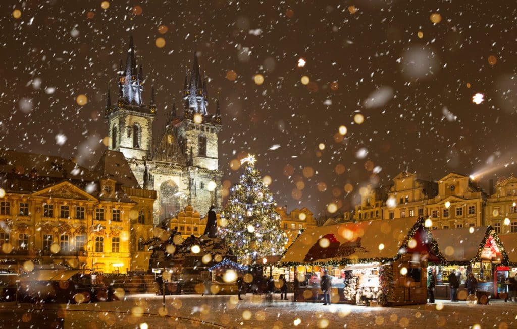 Old Town Prague lit up with Christmas lights, with a decorated tree in the center - one of the best international budget-friendly destinations for Christmas for families.