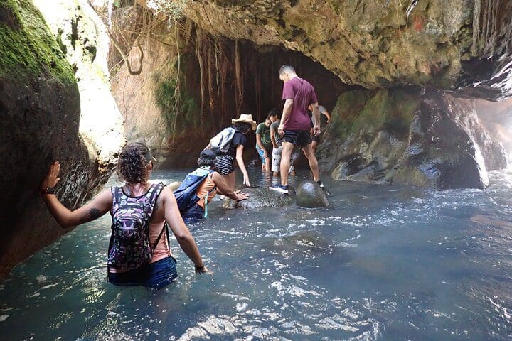 People walk through the water, as experienced on the Private La Leona Waterfall Adventure Hike (Self-Drive) tour.