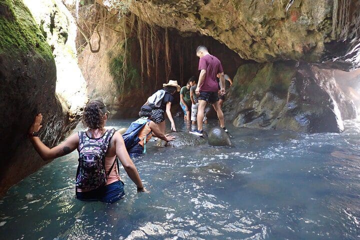 People walk through the water, as experienced on the Private La Leona Waterfall Adventure Hike (Self-Drive) tour.