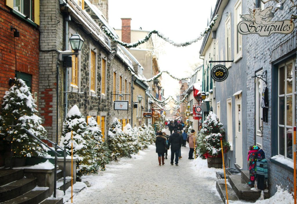 A snowy street in Quebec City, decorated with Christmas lights, one of the best international budget-friendly destinations for Christmas for families.