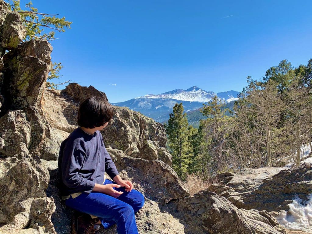 A young boy enjoys a lovely view in Rocky Mountain State Park, one of the best weekend getaways near Denver for families.