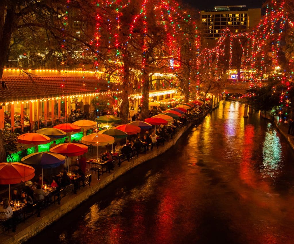 A canal in San Antonio, along with the flanking street lit up for Christmas.
