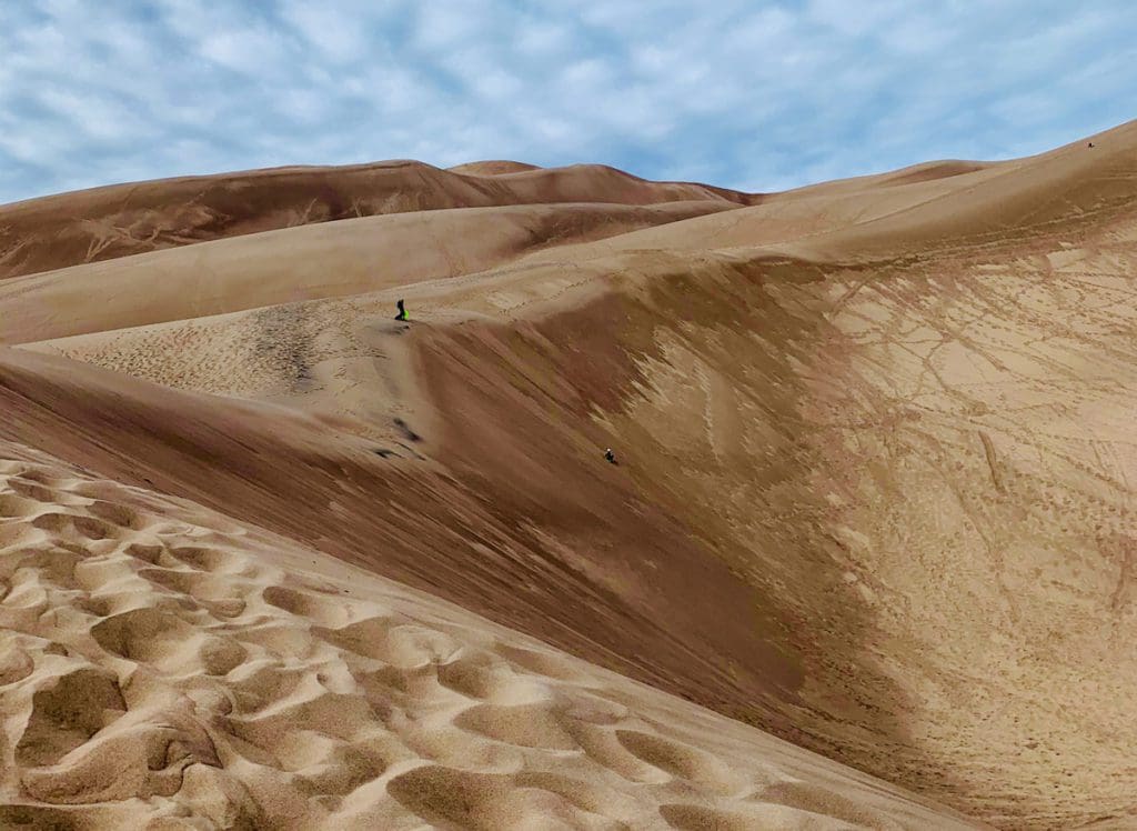 Kids play in the sand at Great Sand Dunes National Park, one of the best weekend getaways near Denver for families.