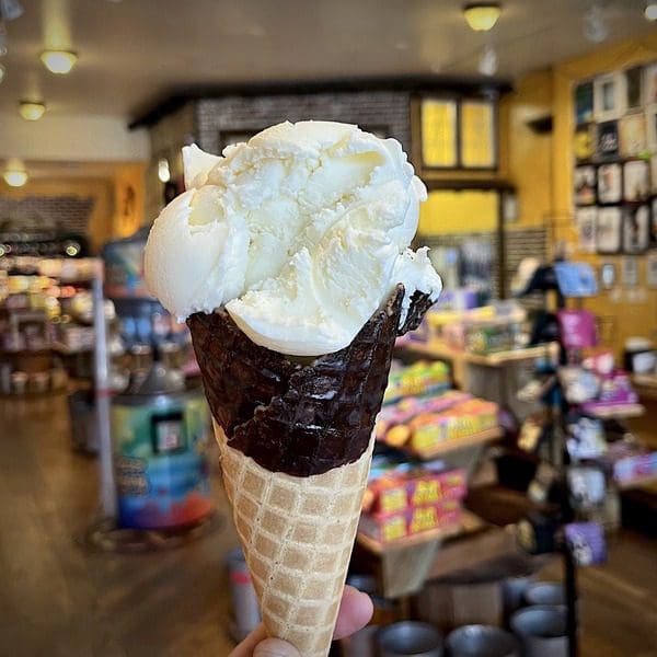 An ice cream cone, held up in the shop for Scrumptious Ice Cream and Candy Shoppe, one of the best dessert spots in Denver with kids.