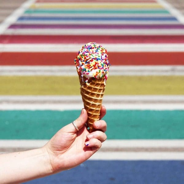 A hand holds out an ice cream cone at Sweet Action Ice Cream, one of the best dessert spots in Denver with kids.