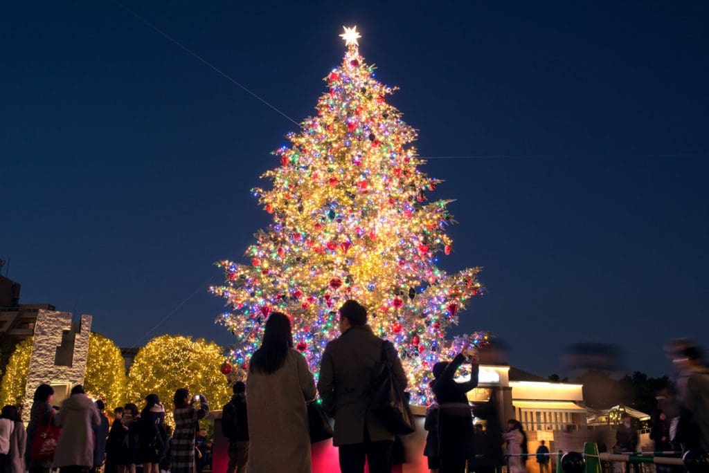 Two people stand in front of a Christmas tree in Tokyo, Japan, one of the best places for Christmas for families in the world.