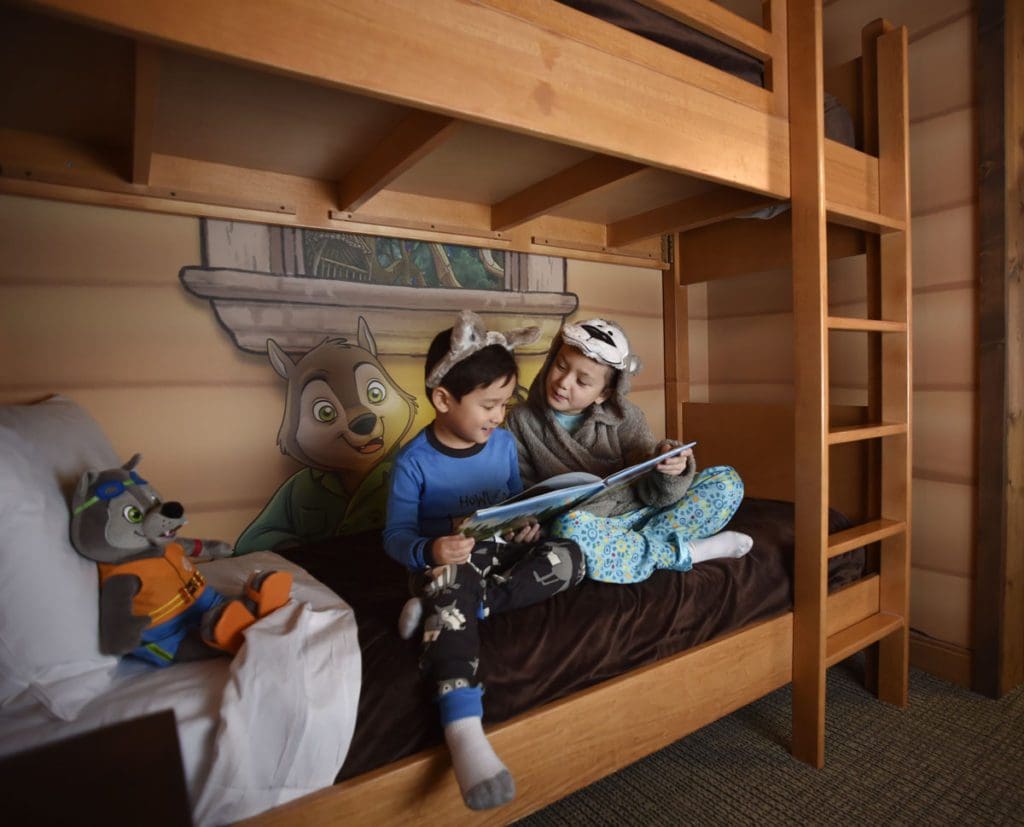 Two kids sit and read a book on a bunk bed in Great Wolf Lodge Minnesota.