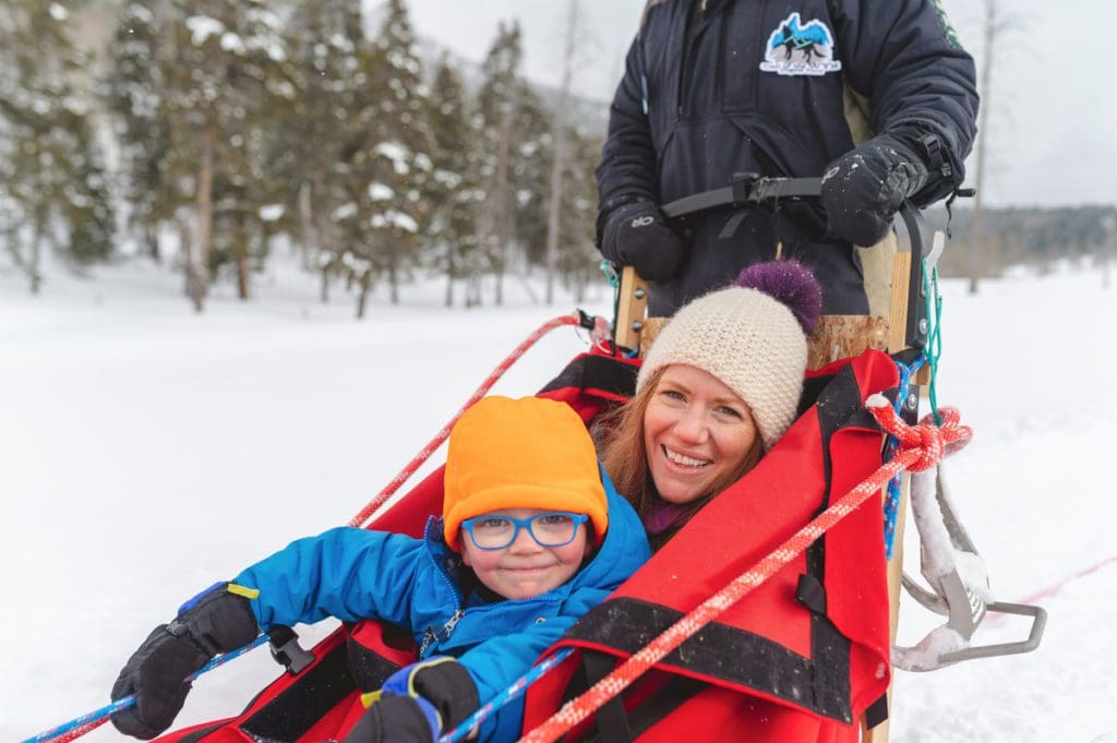 A mom and her young child enjoy a dog sledding experience near Jackson Hole.