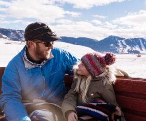 A man and his young child cuddle on a horse-drawn sleigh ride in Jackson Hole.