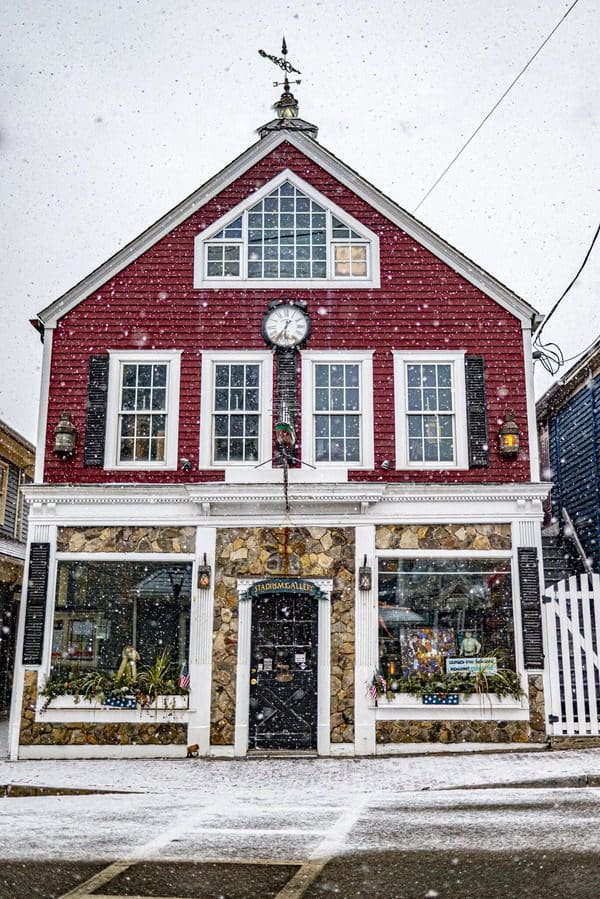 Snow falling on a red building in Maine.