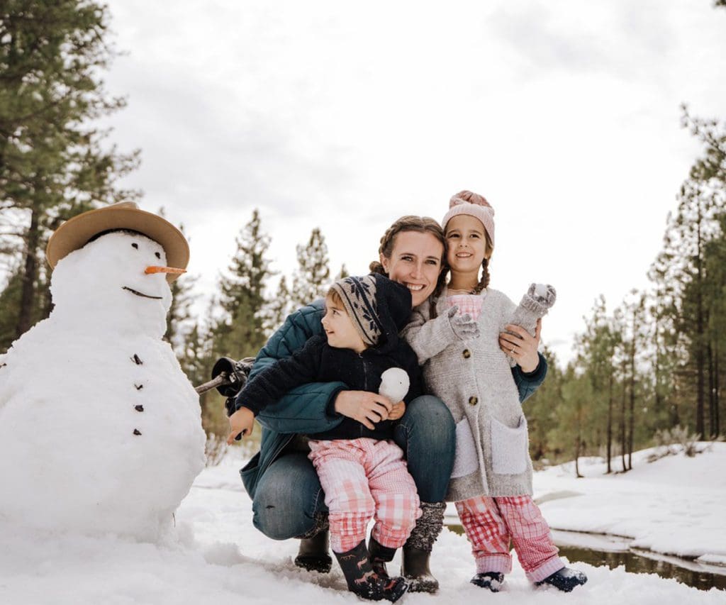 A mom and her young kids build a snowman, while on a Christmas vacation.