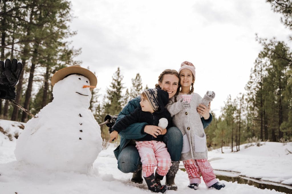 A mom and her young kids build a snowman, while on a Christmas vacation.