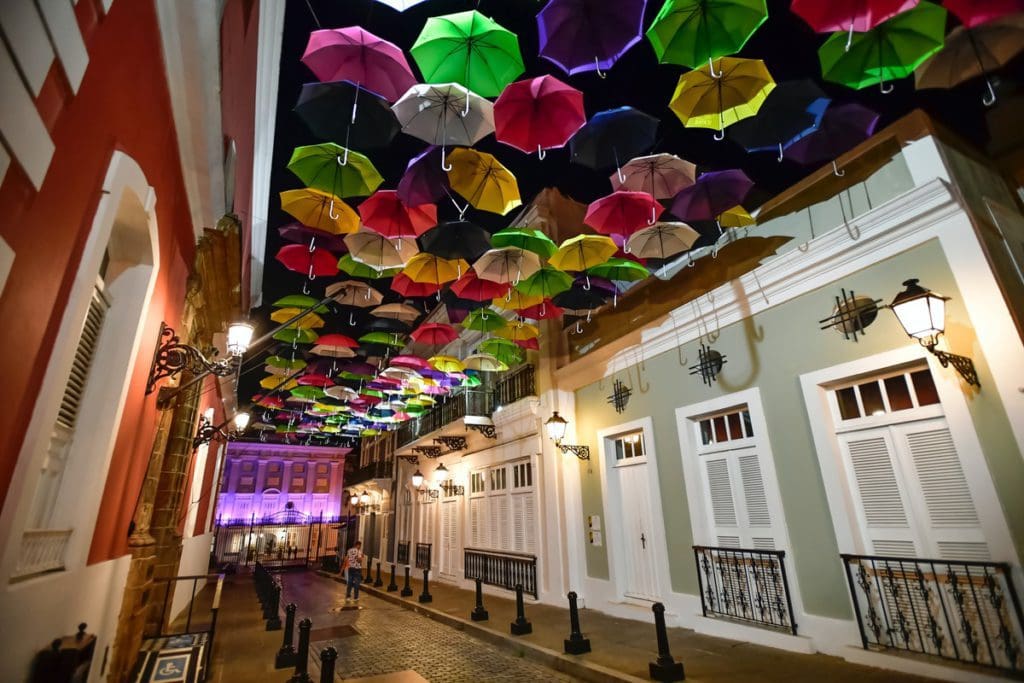A street in Puerto Plata, Dominican Republic, one of the best international budget-friendly destinations for Christmas for families, decorated with colorful umbrellas overhead.