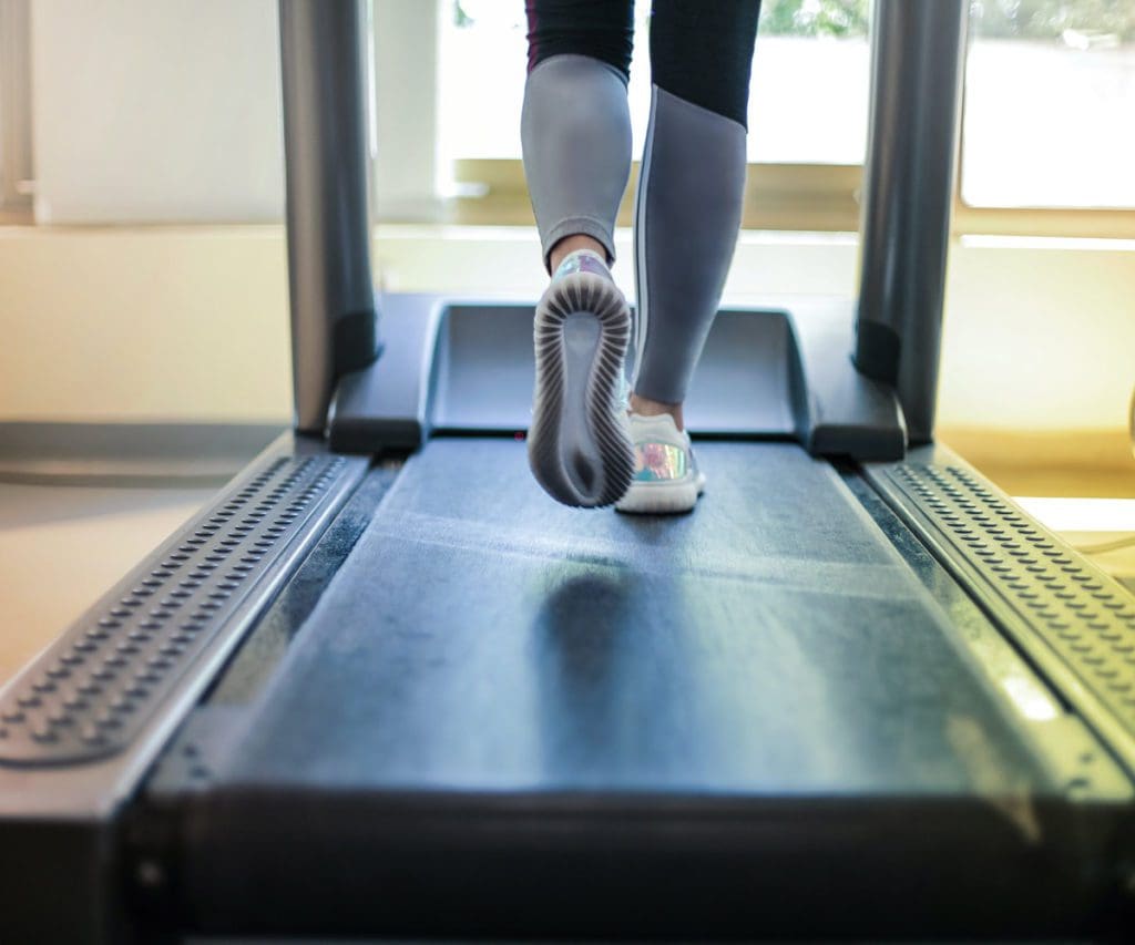 The legs of a woman running on an indoor treadmill.