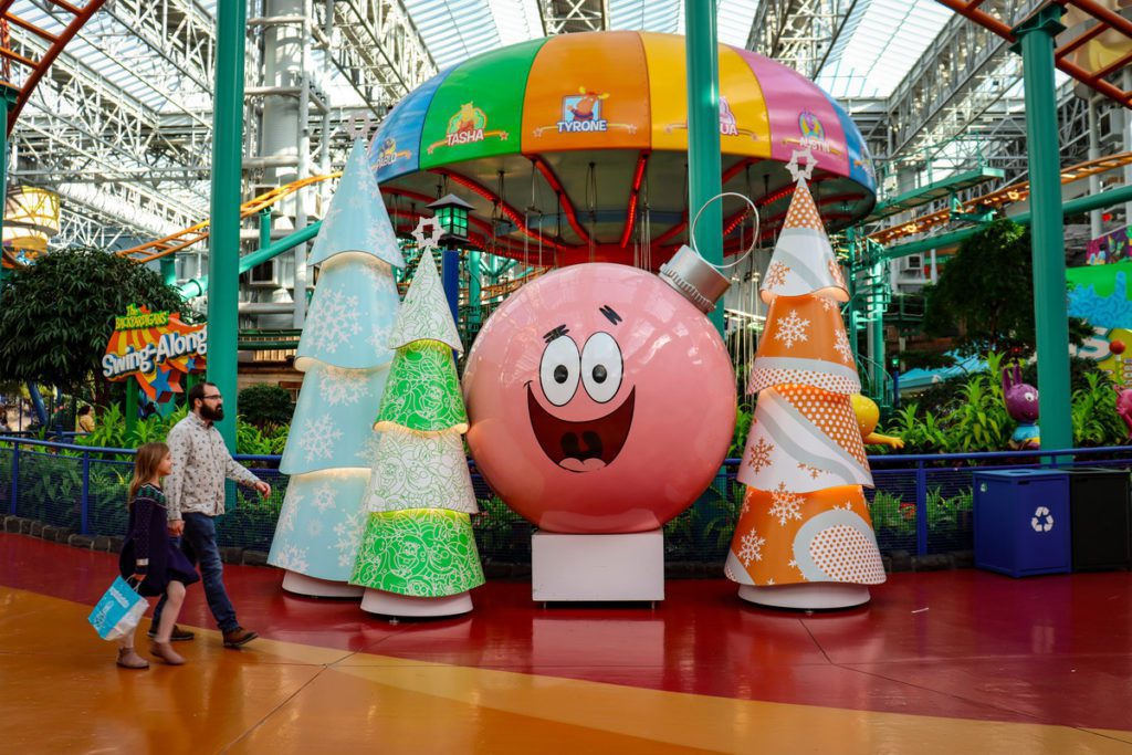A man and his young daughter walk past holiday decorations at Nickelodeon Universe.