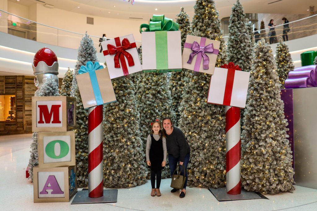 A mom and her young daughter stand together amidst Christmas decor at the Mall of America.