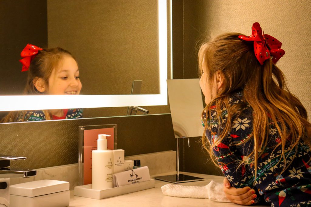 A young girl smiles in a mirror while staying at JW Marriott Minneapolis Mall of America.