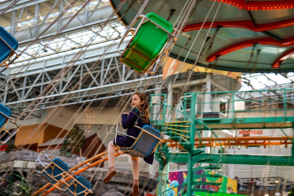 A young girl rides the swing ride at Nickelodeon Universe.