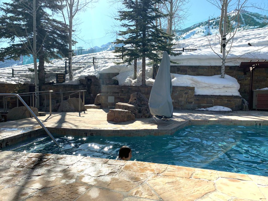 A child swimming in the heated outdoor pool at the Four Seasons Jackson Hole, one of the best hotels in Jackson Hole for families! 