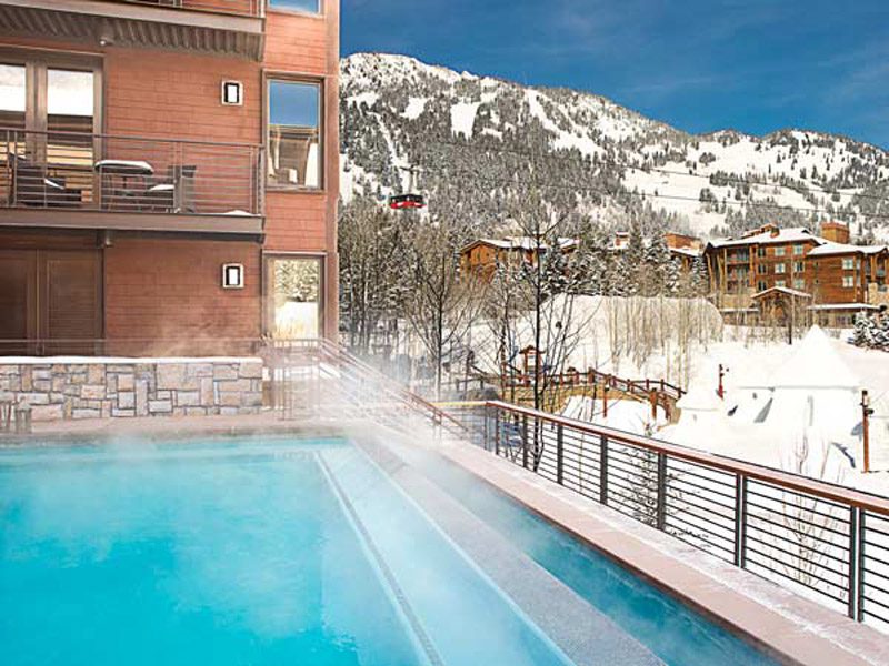 The outdoor pool surrounded by snow at the Hotel Terra Jackson Hole, one of the best hotels in Jackson Hole for families