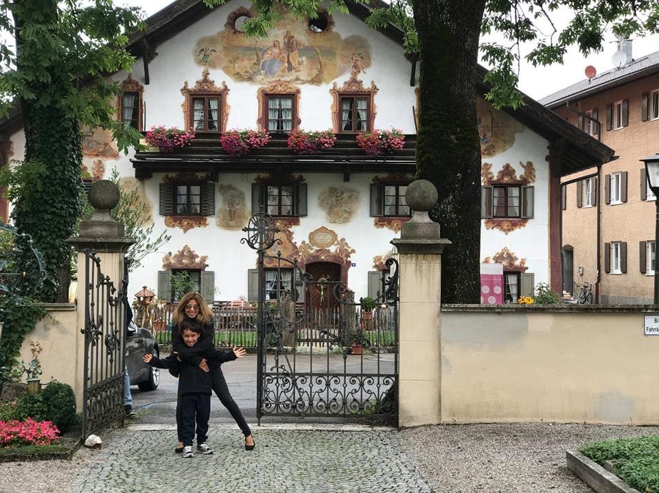 A mother and her young son standing in front of a fairytale-covered house in Oberammergau, Germany