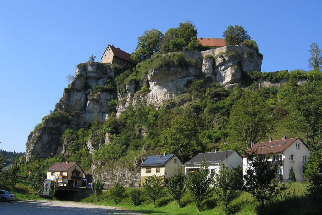 Several houses adorn a cliffside in Pottenstein, Germany, one of the best cities in Germany to visit with kids.