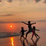 A mother and two children running on the beach during sunset in Oaxaca, Mexico.