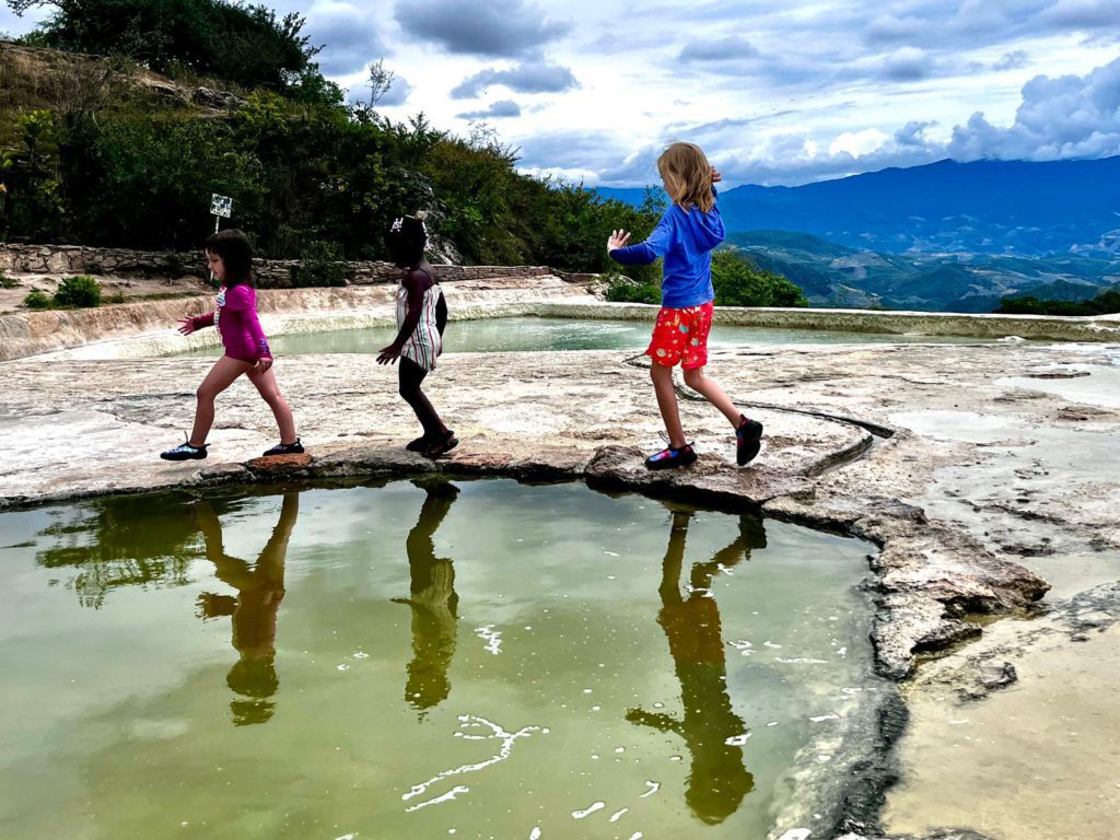 Three kids walking along the landscape in Oaxaca, Mexico. 