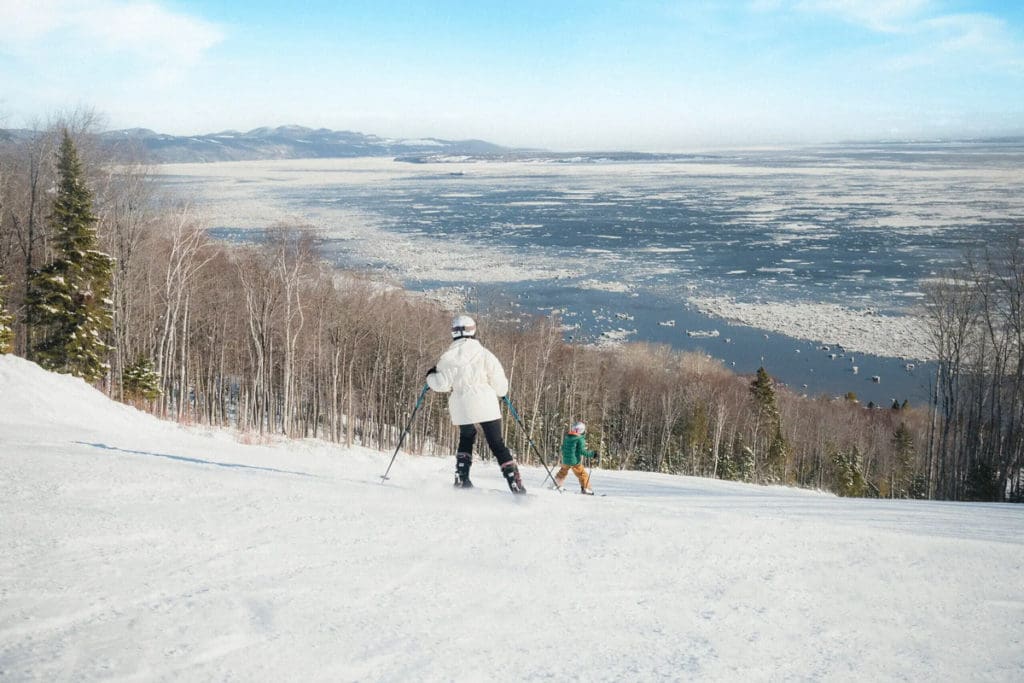 A parent and child skiing in the snow at Club Med Quebec