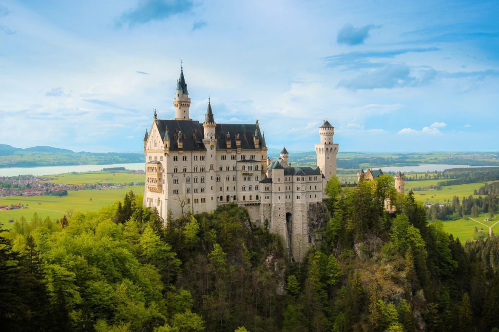 Neuschwanstein Castle atop its mountain top in Germany in the summer. It's one of the best places to visit in Germany with kids! 