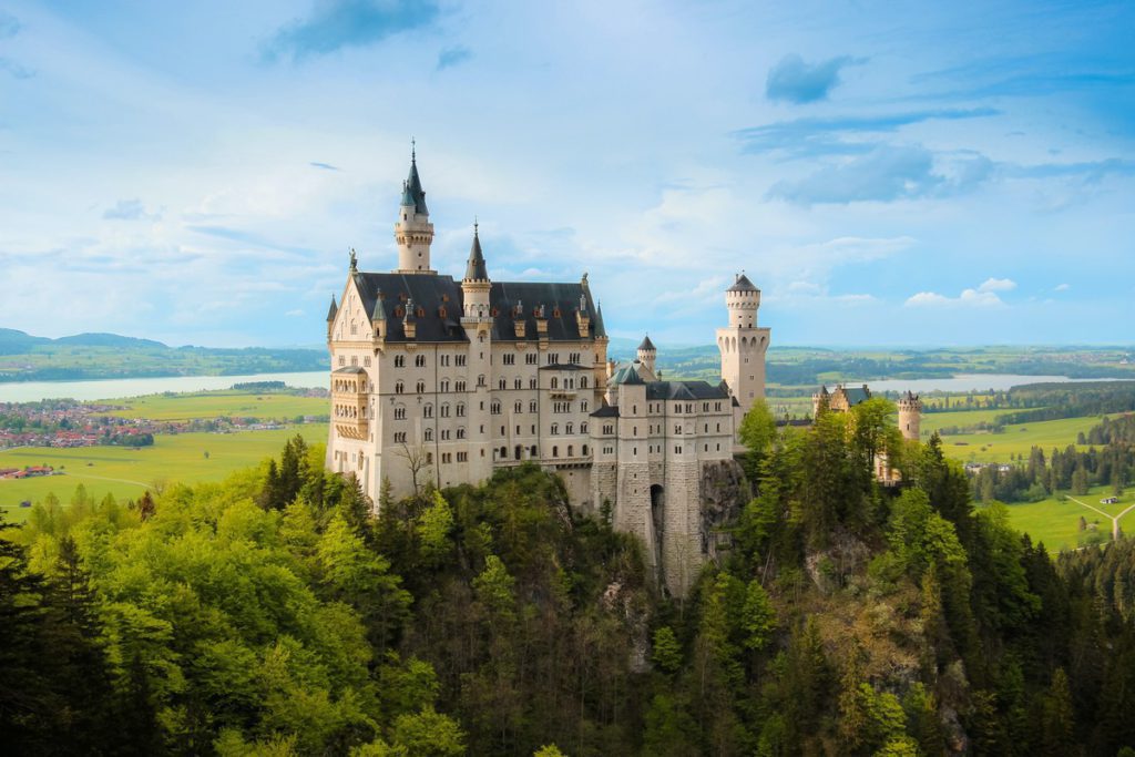 Neuschwanstein Castle atop its mountain top in Germany in the summer. It's one of the best places to visit in Germany with kids!