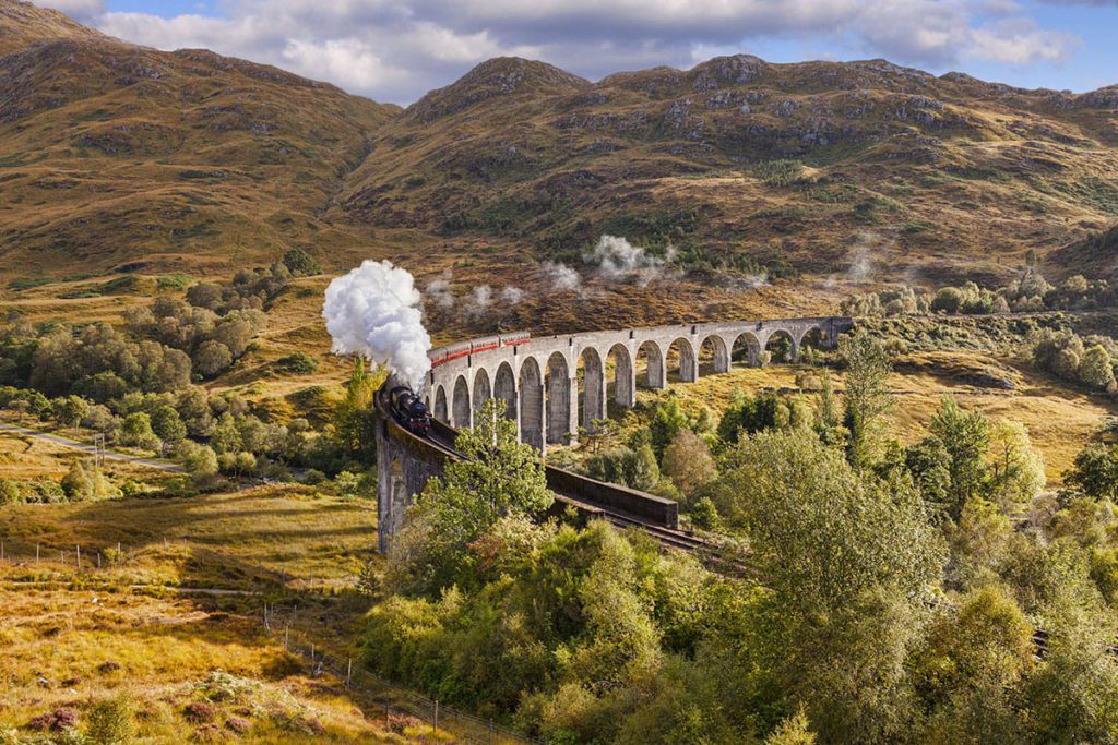 The Hogwarts Express traveling through the landscape in Scotland.