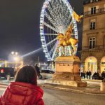 A young girl staring at a Ferris wheel in Paris.