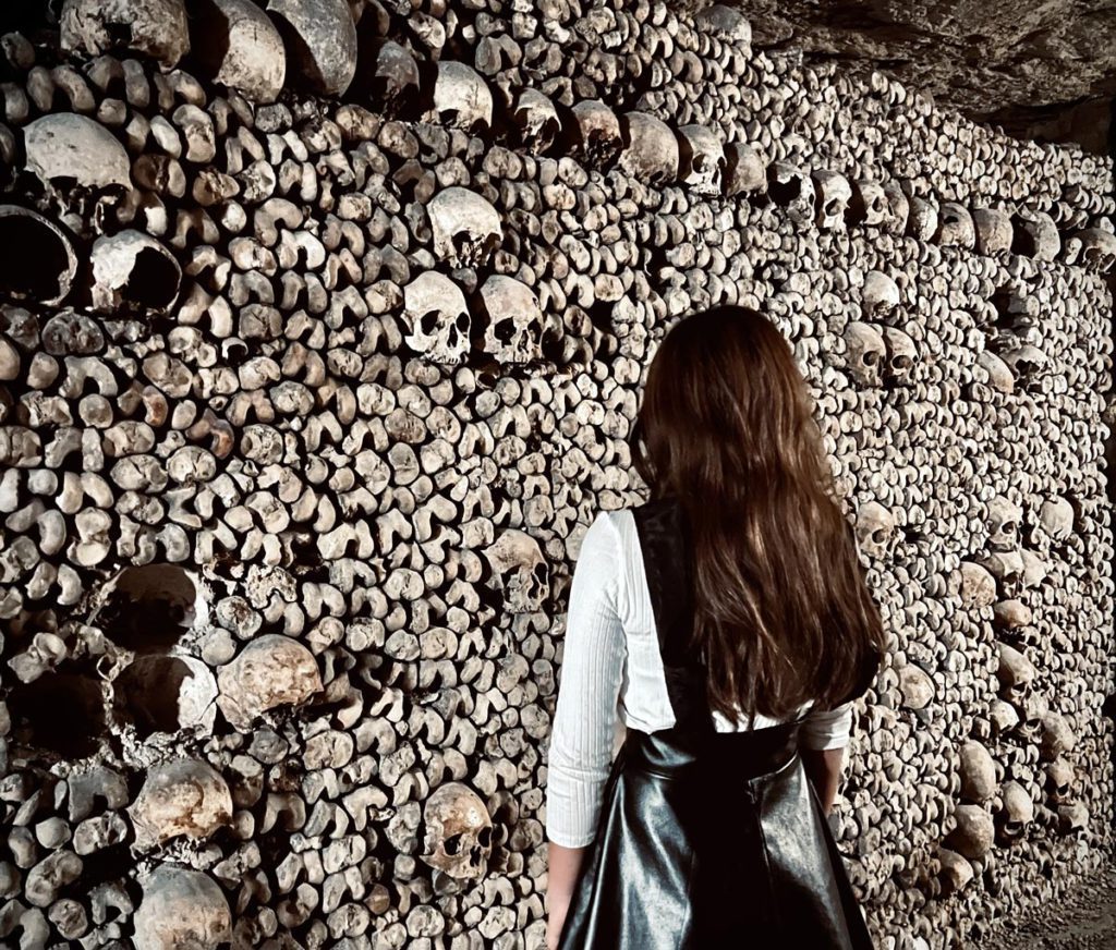 A young girl staring at bones inside the Paris Catacombs. 