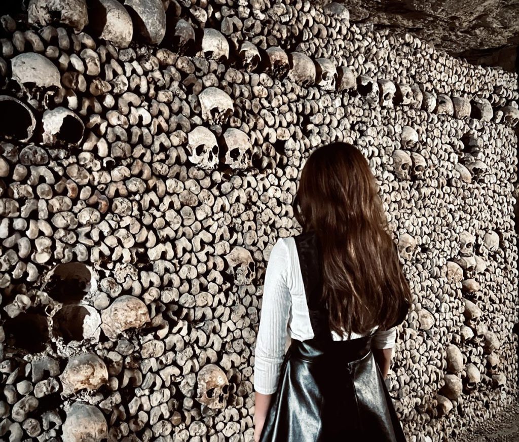 A young girl staring at bones inside the Paris Catacombs.