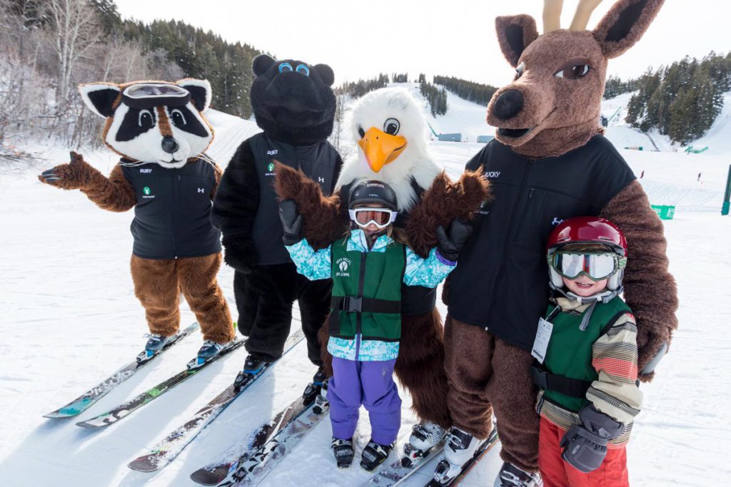 Kid learning to ski with the Deer Valley mascots at Deer Valley Ski Resort, one of the best ski resorts in Utah for families. 