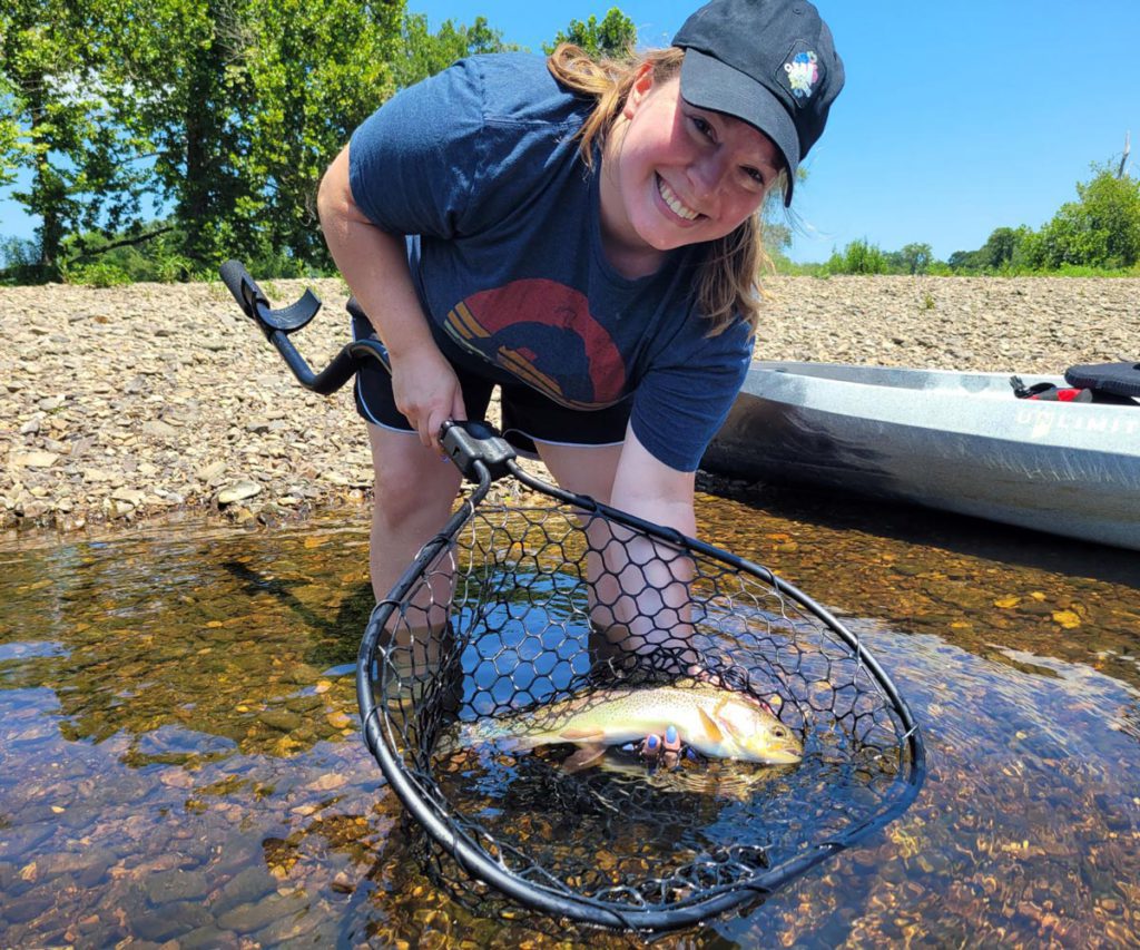 A woman showing off a fish she caught fishing in the Midwest with kids.