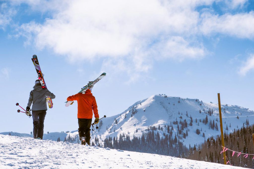 Two skiers carrying their gear at Park City Mountain Resort. 
