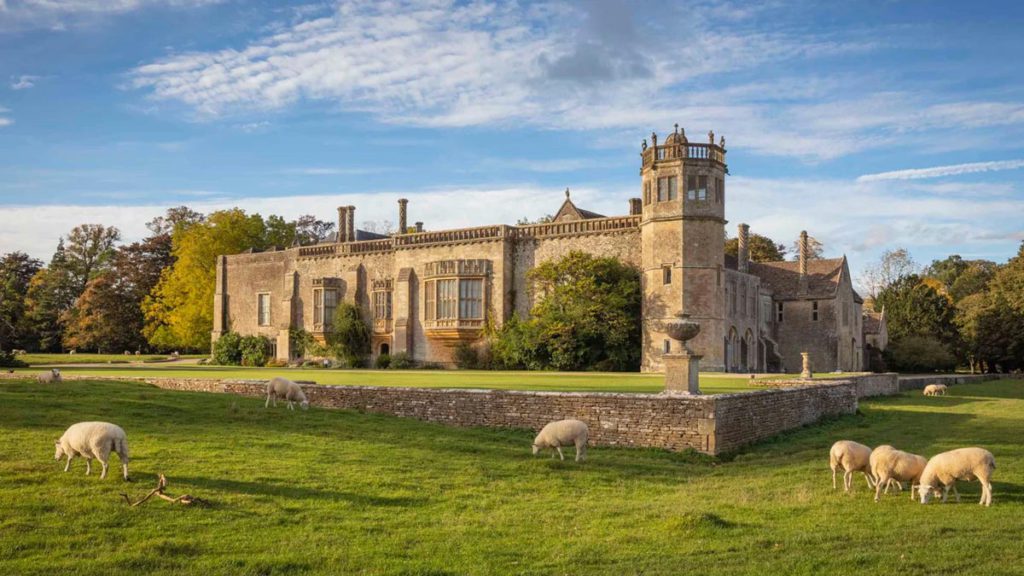 Sheep grazing in the grass in front of Lacock Abbey in England, one of the best Harry Potter destinations for kids. 