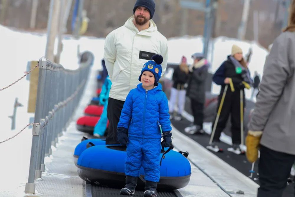 A kid walking with his snow tube at Ski Big Bear at Masthope Mountain