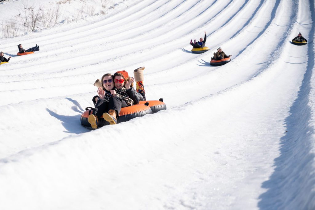 A family snow tubing at Blue Mountain Resort, one of the best places to go snow tubing in The Poconos with kids. 