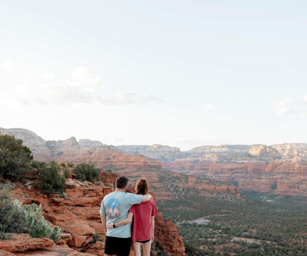 A couple hugging one another while overlooking the red rock in Sedona, one of the best romantic getaways in the United States.