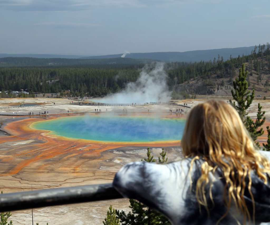 A young blonde girl overlooking the Grand Prismatic Spring in Yellowstone National Park.