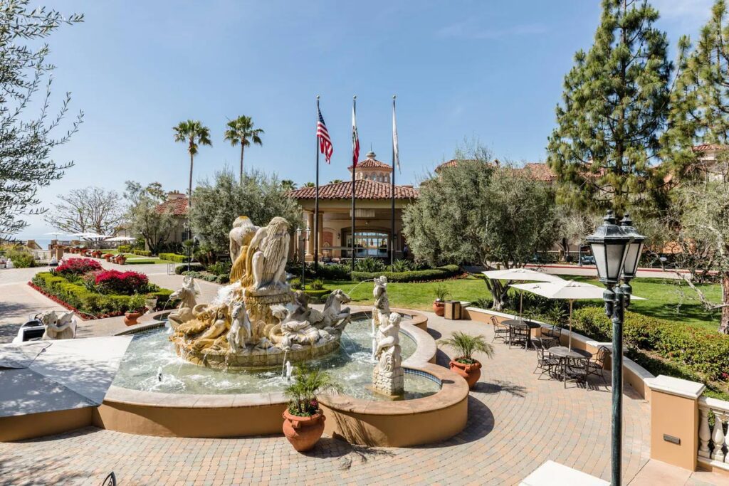 A view of the exterior of the Marriott Newport Coast Villas featuring a fountain and various palm trees.